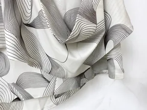 Detail of elegant cream satin fabric with black flowing wave patterns and smooth texture