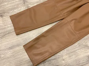 Detail showing smooth texture and stitching of caramel brown faux leather trousers