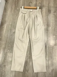 Detail view of high-waist pleated beige PU leather pants with fine glossy finish