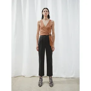 Chic women's outfit with brown sleeveless knit top, black high-waist trousers, and leopard boots