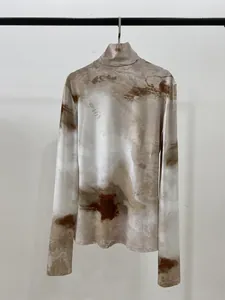 Détail d'un haut à manches longues et col montant avec imprimé marbre brun sur tissu blanc