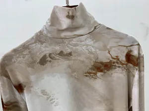 Détail d'un haut à col montant et manches longues avec imprimé marbré marron