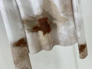 Détail du haut à manches longues blanc montrant les coutures de l'ourlet et l'imprimé abstrait