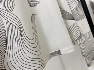 Détail du haut blanc à manches longues avec imprimé abstrait noir et coutures de qualité