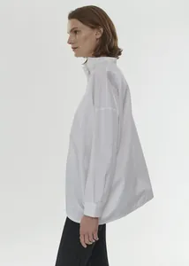 Detail of white oversized cotton shirt with stand-up collar and dropped shoulders