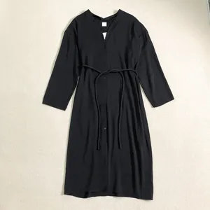 Détail d'une robe noire à col en V avec boutons, ceinture ajustable et tissu texturé