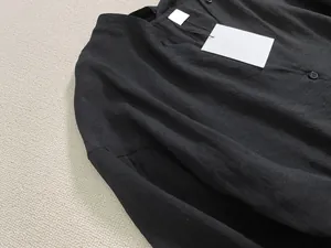 Détail du col d'une robe chemise en lin noir avec boutons et étiquettes de marque