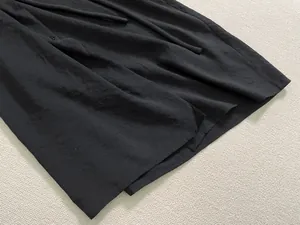 Gros plan détaillé d'une robe noire en coton et lin avec bouton et ceinture à nouer