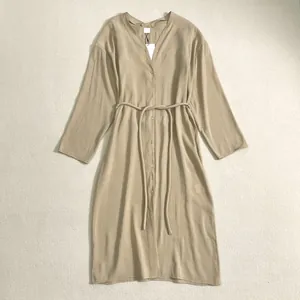 Détail d'une robe chemise à manches longues avec col en V, boutons et ceinture fine