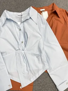 Detailed flat lay of knotted long sleeve shirts in light blue and burnt orange tones