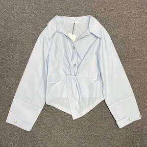 Detail shot of light blue long-sleeved shirt with knot design and irregular hemline