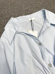 Detail of light blue long sleeve shirt featuring a knot design and engraved buttons