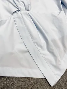 Close-up of light blue knotted shirt detailing fine cotton fabric and neat stitching