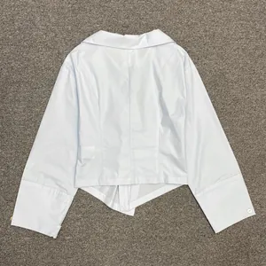 Detail shot of light blue long-sleeved shirt with asymmetrical knot hem and silky finish