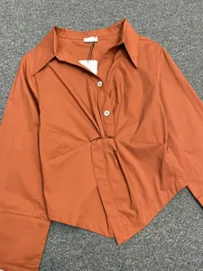 Detailed close-up of the caramel-colored long-sleeve shirt with twisted knot waist detail