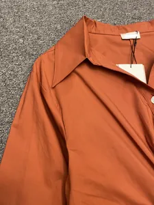 Detail of caramel twisted shirt showing pointed collar and glossy fabric texture
