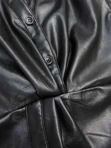 Detailed view of the knotted pleats and black buttons on a premium faux leather shirt