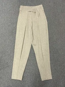 Detail of high-waisted beige trousers with matching belt and natural fabric texture