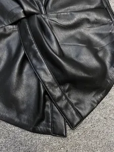 Macro detail of black leather shirt showing the twisted knot design and fine grain texture