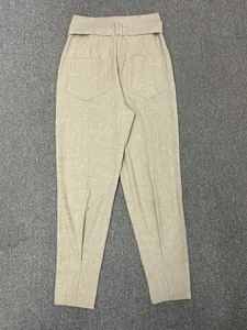 Detail of high-waist beige trousers showing fabric texture, belt and back pockets