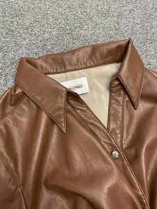 Detailed close-up of brown leather shirt collar and branded buttons on textured background