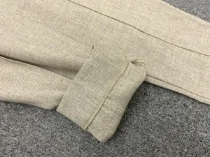 Detailed close-up of cuffed hem and twill fabric texture on high-waist pleated trousers