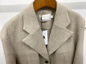 Close-up of beige blazer lapel showing textured fabric weave and quality button detail