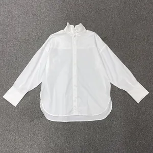 Detail of white blouse featuring a pleated stand collar with traditional frog button closure
