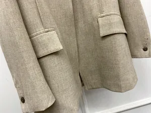 Detailed view of beige oversized blazer featuring flap pockets and textured twill fabric