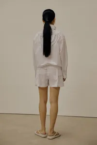 Rear view detail of white minimalist hooded jacket and shorts with clean back tailoring