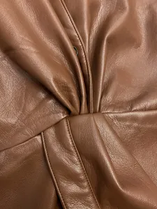 Close-up of brown faux leather fabric with detailed lychee grain and elegant knot design
