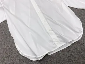 Detailed macro view of white shirt with single-breasted white buttons and curved hemline
