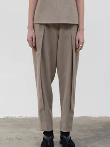 Detail of high-waist pleated trousers and short top set in earthy khaki tones