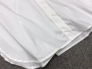 Detailed macro view of white cotton shirt buttons and curved hem with textured fabric