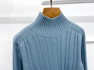 Detail of blue ribbed knit sweater with high neck texture on a wooden hanger