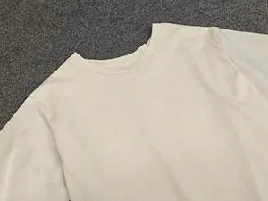 Detailed close-up of the round neckline and smooth cotton fabric of the beige T-shirt