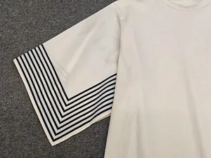 Detailed view of apricot crewneck t-shirt featuring bold black and white striped sleeves