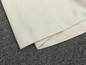Close-up of the fine double-needle hem stitching on a cream striped knit T-shirt