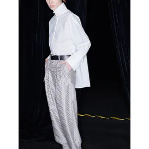White high-neck long sleeve shirt and grey jacquard trousers with a black leather belt