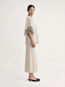 Detail of cream two-piece skirt set showing striped cuffs and structured cotton fabric