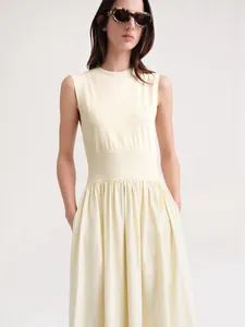 Détail d'une robe longue sans manches jaune clair avec taille ajustée et bas plissé