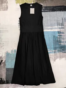 Robe longue noire sans manches avec taille haute plissée, vue à plat sur un tapis