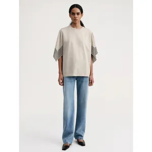 Minimalist beige round neck T-shirt with black and white striped flared sleeves and jeans