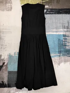 Robe noire sans manches coupe trapèze avec taille cintrée et jupe plissée présentée à plat