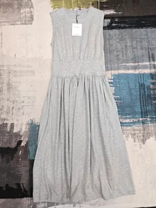 Détail de la robe grise sans manches avec taille haute et col rond sur tapis texturé