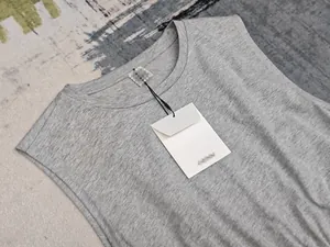 Détail de la robe sans manches grise à col rond avec étiquettes sur fond de tapis blanc
