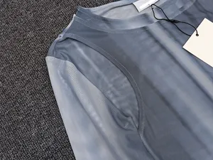 Close-up of semi-transparent gradient mesh top with round neckline and fine stitching