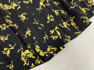 Detailed close-up of yellow floral print fabric with a single black button on a skirt