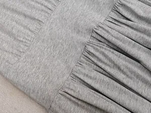 Détail macro de la texture du tissu plissé en tricot gris et couture de la robe
