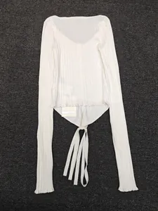 Detail view of white ribbed knit cardigan with U-neck and decorative tie straps